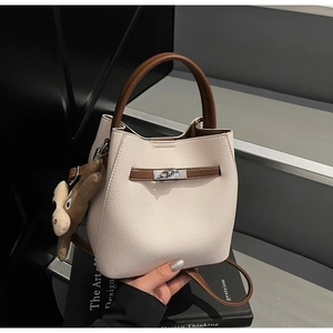 Detail of beige litchi leather bucket bag with silver buckle and plush deer charm