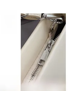 Detailed macro view of high-quality silver metal zipper on an ivory leather handbag