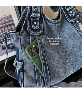 Detail of vintage blue denim tote showing a front zipper pocket with a smartphone inside