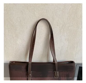 Close-up of adjustable brown leather handle and retro printed fabric on a tote bag