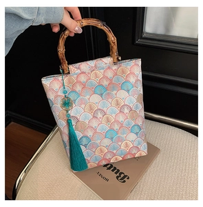 Detailed embroidery on Chinese-style handbag with bamboo handle and blue tassel charm