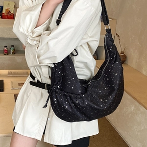 Detail of black Hobo bag featuring silver star print and adjustable crossbody strap