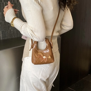 Detail of a brown quilted mini crossbody bag featuring a cute horse patch and glossy finish