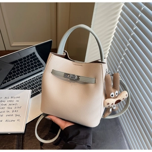 Close-up of cream textured leather bucket bag with light blue handles and a metal turn-lock