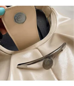 Dettaglio della chiusura magnetica e finiture metalliche su borsa a pieghe crema
