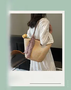 Detail of striped woven straw tote with brown leather strap and red paisley scarf accent