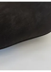 Detail view of premium black leather texture with gold foil stamped lettering on the handbag