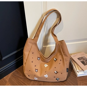 Detail shot of brown canvas tote bag featuring cute cartoon animal embroidery and brand tag