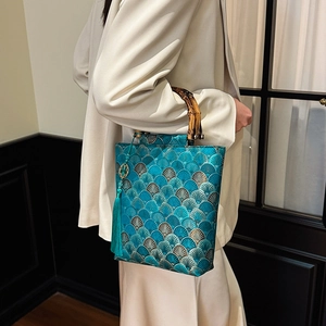 Detailed embroidery and bamboo handle on a Chinese style teal green handbag with tassel