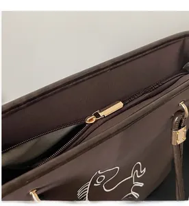 Detail showing smooth gold metal zipper and white horse embroidery on dark brown tote bag