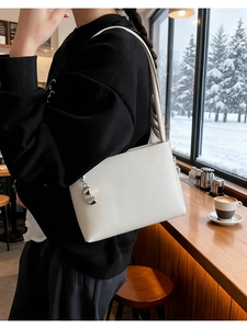 Minimalist white shoulder bag with silver metallic bean charm on black sweatshirt