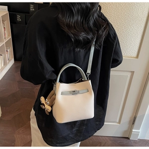 Litchi pattern beige bucket bag with light blue straps and plush bear charm on model
