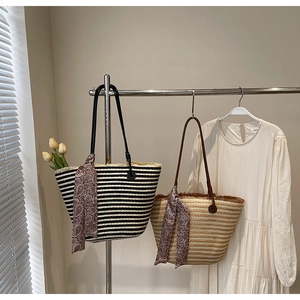 Detail of woven straw tote bags featuring colorful silk scarves and faux leather straps