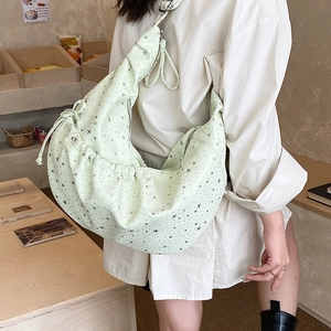 Detail of mint green pleated crescent bag with black star prints and drawstring design