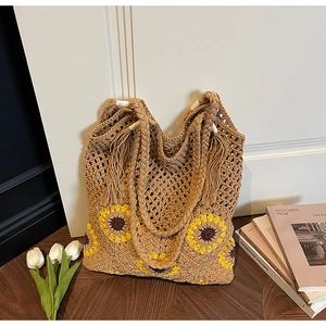 Detail of hand-woven straw tote bag with sunflower crochet patterns and tassel straps