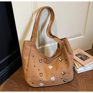 Detail of embroidered animal patterns and brand label on a large brown canvas tote bag