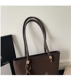 Detail showing high-quality dual shoulder straps and gold metal hardware on brown leather tote