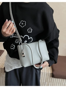 Detail of grey-green crossbody bag with silver moon pendant and metal chain strap