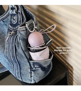 Detail view of denim tote bag side pocket holding a purple capsule umbrella for easy storage