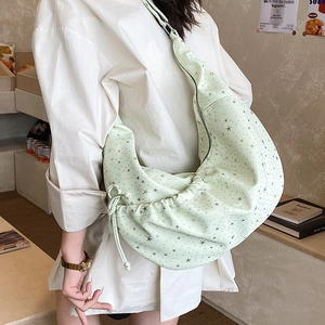 Detail showing mint green star-printed dumpling bag with drawstring ruching on the side