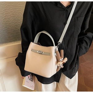 Detail view of beige lychee leather bucket bag with blue strap and metal lock closure