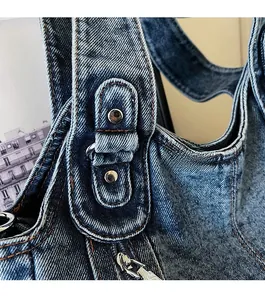Close-up of deep blue washed denim tote bag with silver zippers and rivet details