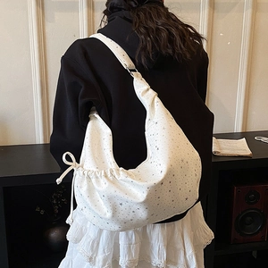 Detail of white star print dumpling bag with adjustable shoulder strap and bow tied side