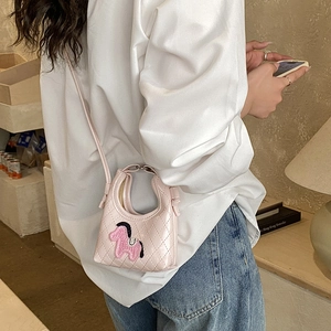 Detail of pink mini quilted crossbody bag with cute pony embroidery on a model