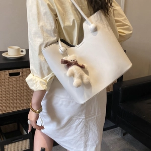 Minimalist white leather tote bag with a cute teddy bear charm for daily commuting