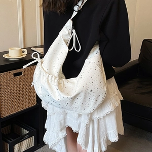 Side view of a white crescent moon bag featuring star patterns and black adjustable strap