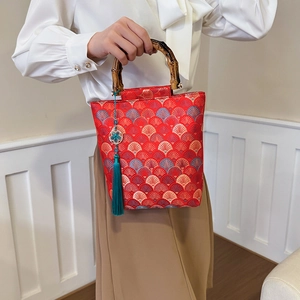 Detail of red embroidered handbag with traditional bamboo handle and green tassel pendant