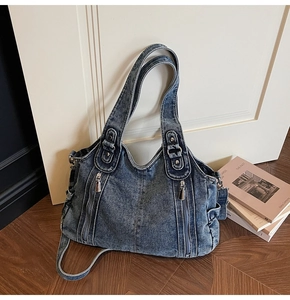 Detailed close-up of blue washed denim tote bag with vintage metal zippers and rivets