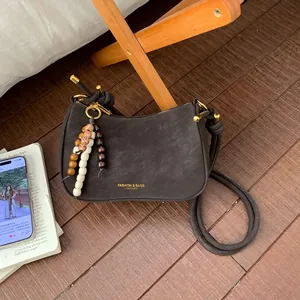Close-up of retro dark brown hobo bag with wood bead charm and knotted shoulder strap