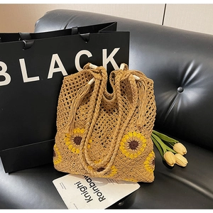 Detail of crochet tote bag with sunflower pattern and fringe tassels on black sofa