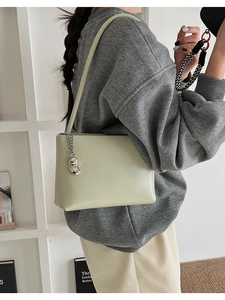 Detail showing smooth light green shoulder bag with silver bean-shaped metal pendant