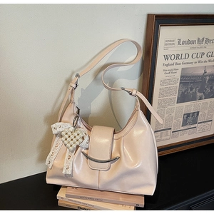 Dettaglio borsa a pieghe beige con fibbia in metallo e accessorio ciondolo cuore perla