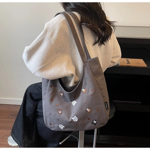 Detail of large grey canvas tote bag with embroidered cat and bear motifs for daily use