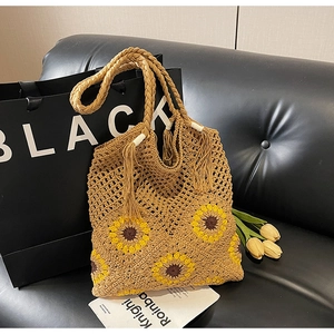Detail view of khaki hand-woven tote bag with sunflower pattern and fringe tassels