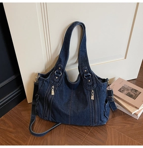Detail of dark blue denim tote bag showing functional side pocket and silver hardware