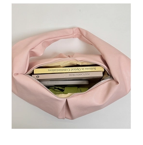 Detail showing spacious interior of pink pleated hobo bag with books and daily essentials