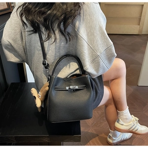 Detail of black lychee grain leather bucket bag with white stitching and silver turn-lock