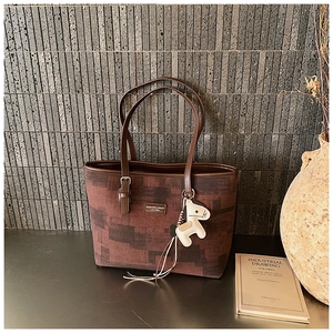 Detail of contrast color tote bag with leather handles and white horse charm pendant