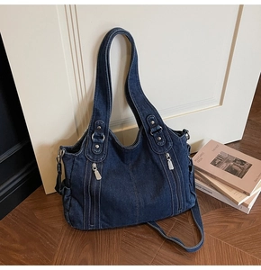 Detailed macro view of large dark blue denim tote bag with silver zippers and strap