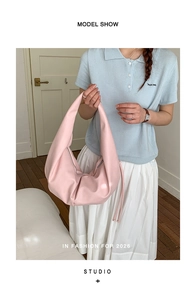 Pink pleated leather hobo bag for women worn on shoulder in a stylish lifestyle scene