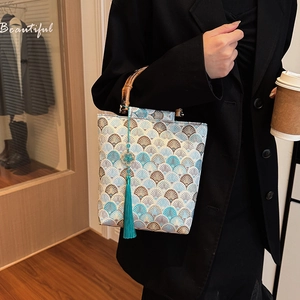 Detail of jacquard fabric bag with shell pattern, bamboo handle, and teal tassel charm