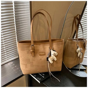 Detail of khaki tote bag with brown leather trim and cute white horse charm