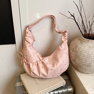 Pink crescent shoulder bag with star print and pleated texture on vintage suitcase