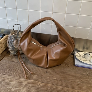 Detail view of brown pleated hobo bag with silver zipper and double long leather tassels