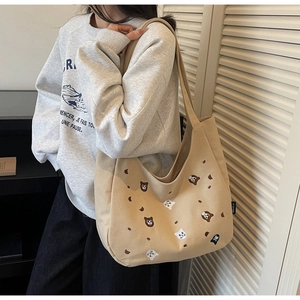 Detailed close-up of cute animal embroidery on a beige canvas tote bag with side label