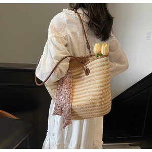 Detail of handwoven straw tote with leather straps and floral silk scarf accessory